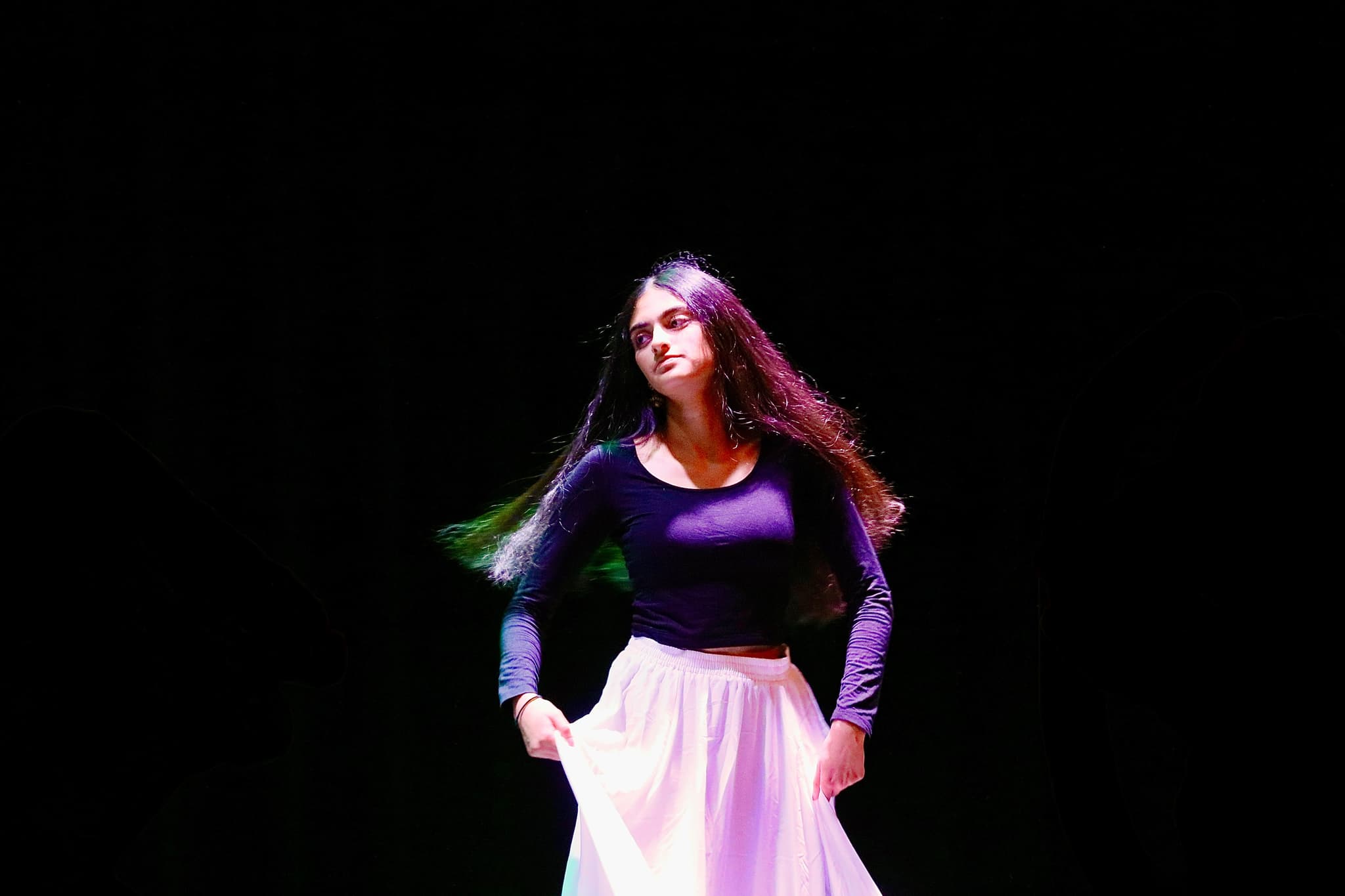 Solo dance performance — dark stage, hair in motion