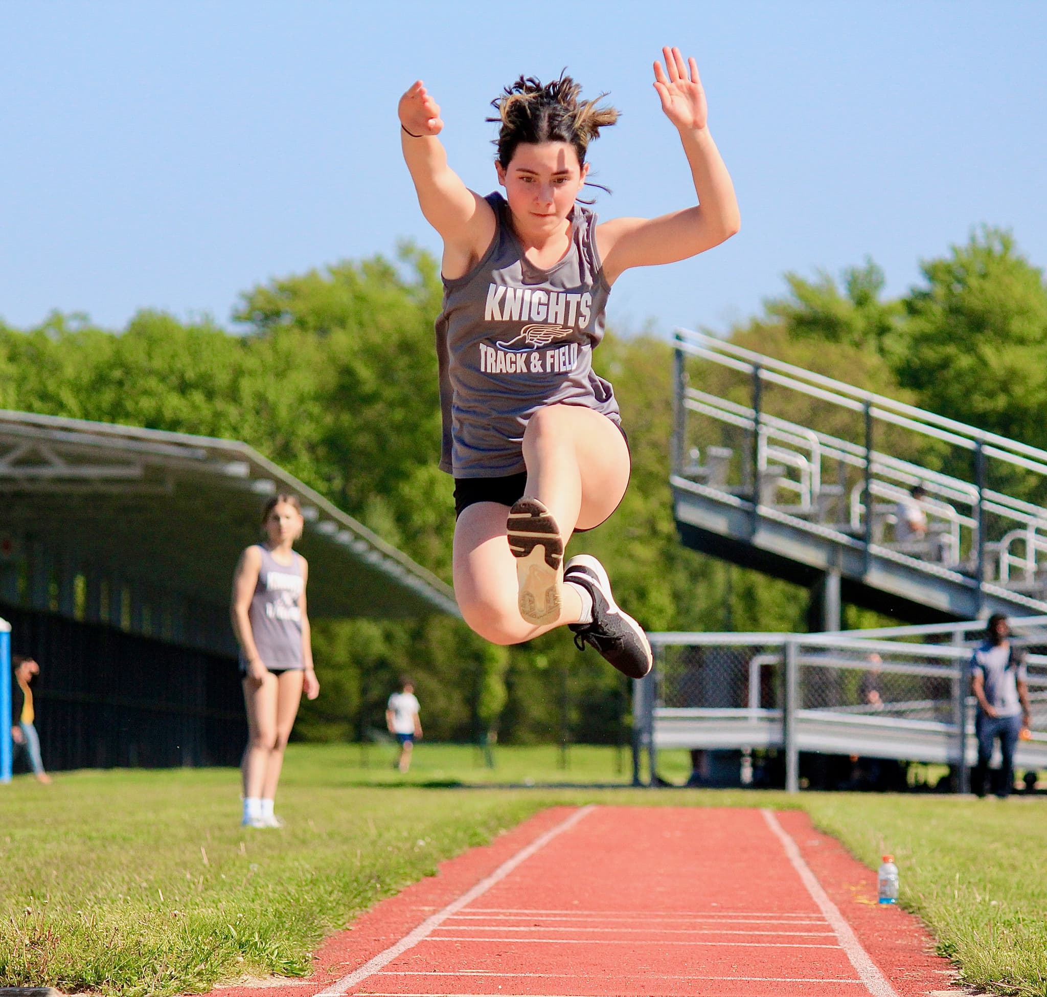 Track and field athlete suspended mid-air in a long jump