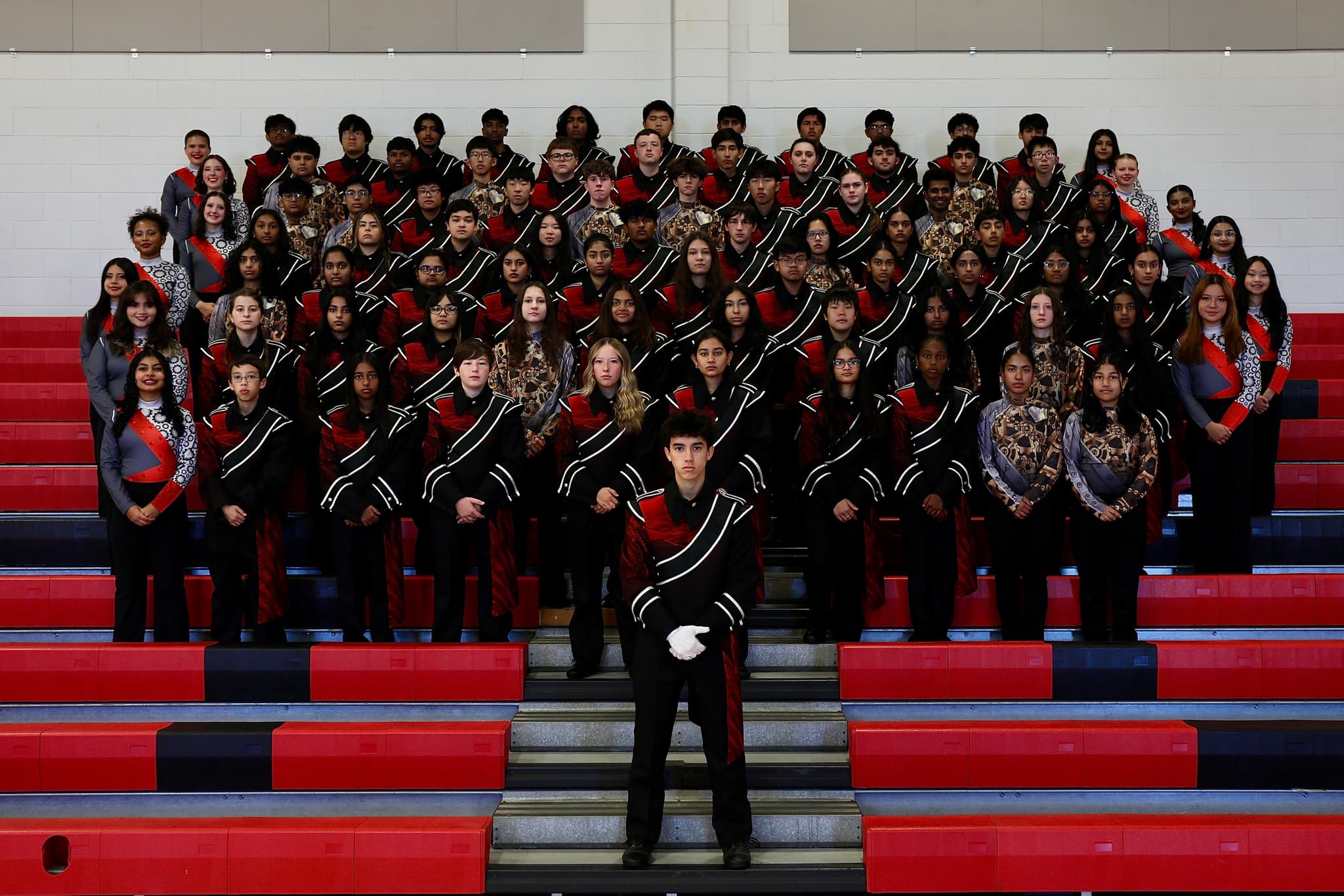 Marching band posed in gymnasium bleachers