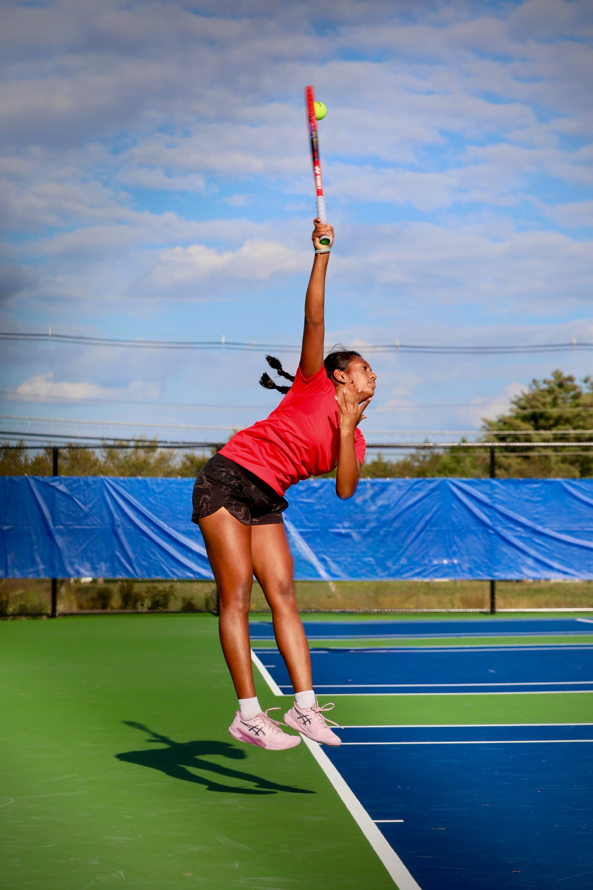 Tennis player launches into a serve, mid-air